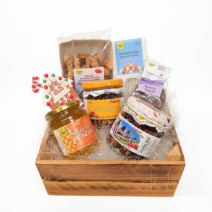 Eleganti cesti regalo natalizi artigianali con prodotti tipici del Trentino, confezionati con cura su sfondo bianco con ombre naturali. Ogni confezione è personalizzabile e include miele di acacia, biscotti, infusi selezionabili, caramelle e accessori natalizi unici. Perfetti per regali di Natale originali e raffinati.